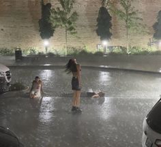 two women are standing in the middle of a parking lot while one woman is laying on the ground