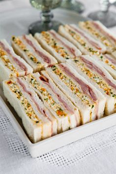 several sandwiches are arranged on a white platter and ready to be served at a party