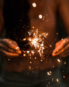 a woman holding out her hands with fireworks in the air above her and on her chest