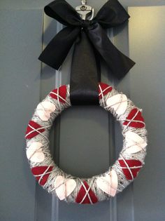 a red and white wreath on the front door with a black bow hanging from it