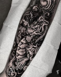 a black and white dragon tattoo on the arm