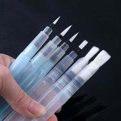 a hand is holding several plastic tubes with black tips and white tip on each end