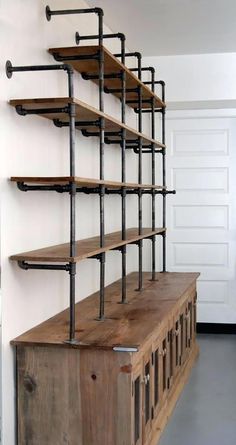 an old wooden shelf with metal pipes on the top and shelves above it, in a room