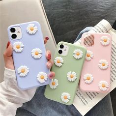 three phone cases with daisies on them, one is pink and the other is green