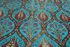 an intricately designed fabric with red and blue designs on the top, in various colors