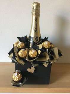 a bottle of champagne and some chocolates in a black box on a wooden table