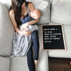 a woman sitting on a couch holding a baby next to a sign that says amazon needs a button sleeping pillow