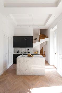 an instagram photo of a white kitchen with black cabinets and marble island in the middle