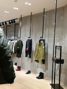 a clothing store with lots of coats and boots hanging on the wall next to each other