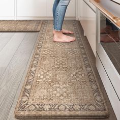 a woman standing on top of a rug in a kitchen