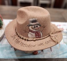 a brown hat with a snowman drawn on the side and words written below it