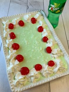 a cake with cherries and whipped cream on it next to a bottle of soda