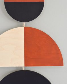 two circles with black, orange and white painted on them hanging from the wall next to each other