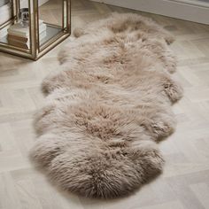 a long haired sheepskin rug is on the floor next to a mirror and lamp