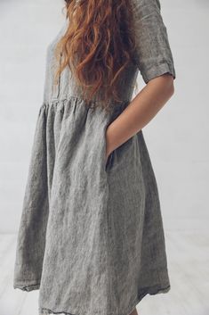 a woman with long red hair wearing a gray dress