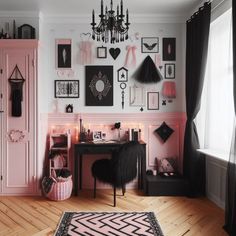 a pink and black room with pictures on the wall, chandelier, rug and desk