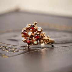 This stunning 9ct gold dress ring showcases four vibrant garnets, beautifully complemented by five sparkling dainty opals. The ring's design is inspired by the Victorian period, featuring intricate scrollwork to the shoulders for a touch of antique elegance. Garnets have long been cherished for their believed protective powers, thought to safeguard travellers and illuminate the night, symbolising guidance and safety. This rich symbolism has made garnets a timeless favourite in jewellery for both Garnet Dress, Giacomo Casanova, Victorian Period, Dress Rings, Vintage Ring, Gold Dress, Rings Statement, Vintage Rings, Ring Designs