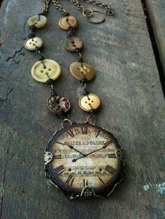 an old clock necklace with buttons attached to it's chain on a wooden surface