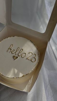 a white cake with gold lettering on it in a box