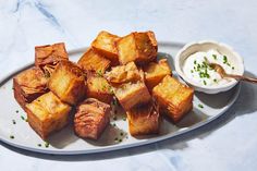 a white plate topped with cubed bread next to a bowl of sour cream