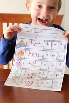 a young boy is holding up a printable letter recognition sheet to show his handwriting