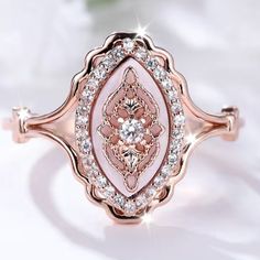 a pink ring with diamonds on it and a rose in the middle, sitting on a white surface