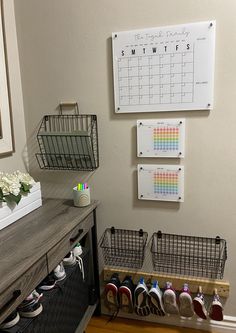 there is a calendar on the wall next to some baskets with shoes hanging from them