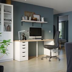 a computer desk with a monitor and keyboard on top of it next to a book shelf