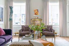 a living room filled with lots of furniture and windows covered in drapes, leopard print throw pillows