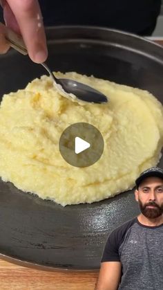 a man is cooking mashed potatoes in a skillet with a spoon on the side