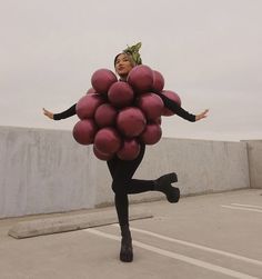 a woman in black is holding a bunch of pink balloons while standing on her legs