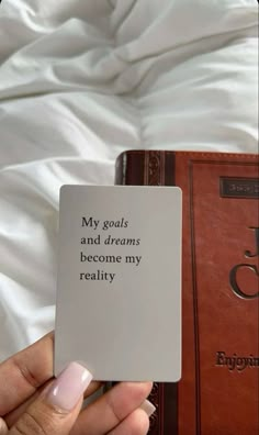 a woman holding up a card with the words my goals and dreams become my reality