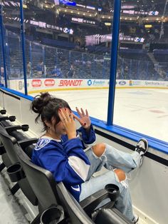 a woman is sitting on the bench at an ice hockey game and covering her face