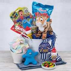 a stuffed animal sitting in a bucket filled with candy and candies next to other items