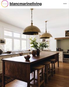 the kitchen is clean and ready to be used for cooking or dining, with two pendant lights hanging over the island