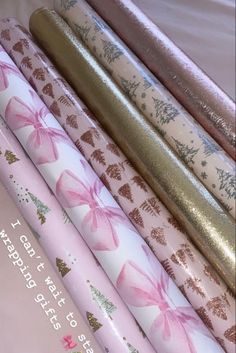 pink and gold wrapping paper with bows on them are stacked next to each other in a pile