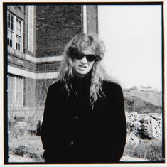 a black and white photo of a woman with long blonde hair in front of a building