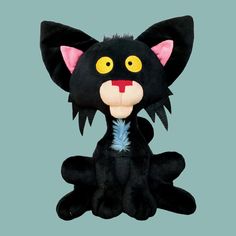 a black cat stuffed animal with yellow eyes and big ears sitting on a blue background