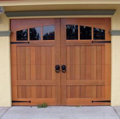 two wooden garage doors with windows on each side