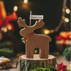 a wooden reindeer ornament sitting on top of a tree stump next to christmas decorations