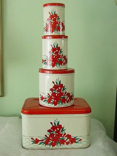 three red and white containers stacked on top of each other with flowers painted on them