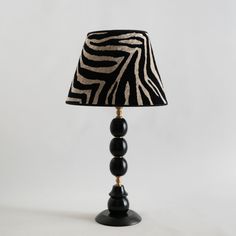 a zebra print lamp shade on a black and white base with two wooden bead lampshades