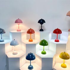 many different colored lamps are on display in a room with white walls and flooring