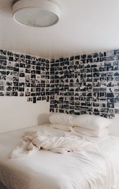 an unmade bed with many pictures on the wall