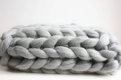 a gray and white knitted cushion sitting on top of a table next to a wall