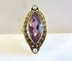 Originally $1,200.00 Circa 1900. Gorgeous Marquis Amethyst ring accented by pearls and beautiful engraving and open work detail in 14KT gold. A very elegant antique cocktail ring. The Bezel set Amethyst measures approximately 18mm x 8mm. The mounting/top of the ring, measures (point to point) approximately 28mm. The width of the mounting is approximately 11mm. The ring is a size 7 3/4 and can be sized. Customer Care: I will help guide you throughout the entire process of your ring selection. I o Luxurious Rings, Antique Cocktail Ring, Antique Rings Vintage, Amethyst Ring, Antique Rings, Pearl Ring, 14kt Gold, Stacking Rings, Cocktail Rings