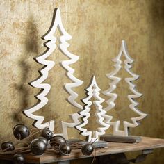 three wooden christmas trees sitting on top of a table next to bells and a mouse