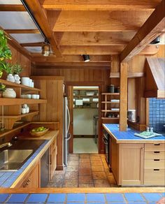 a kitchen with blue tile flooring and wooden walls, along with open shelving