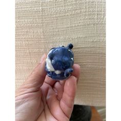 a hand holding a small blue and white animal