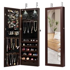 an open wooden jewelry cabinet next to a mirror with necklaces and earrings on it